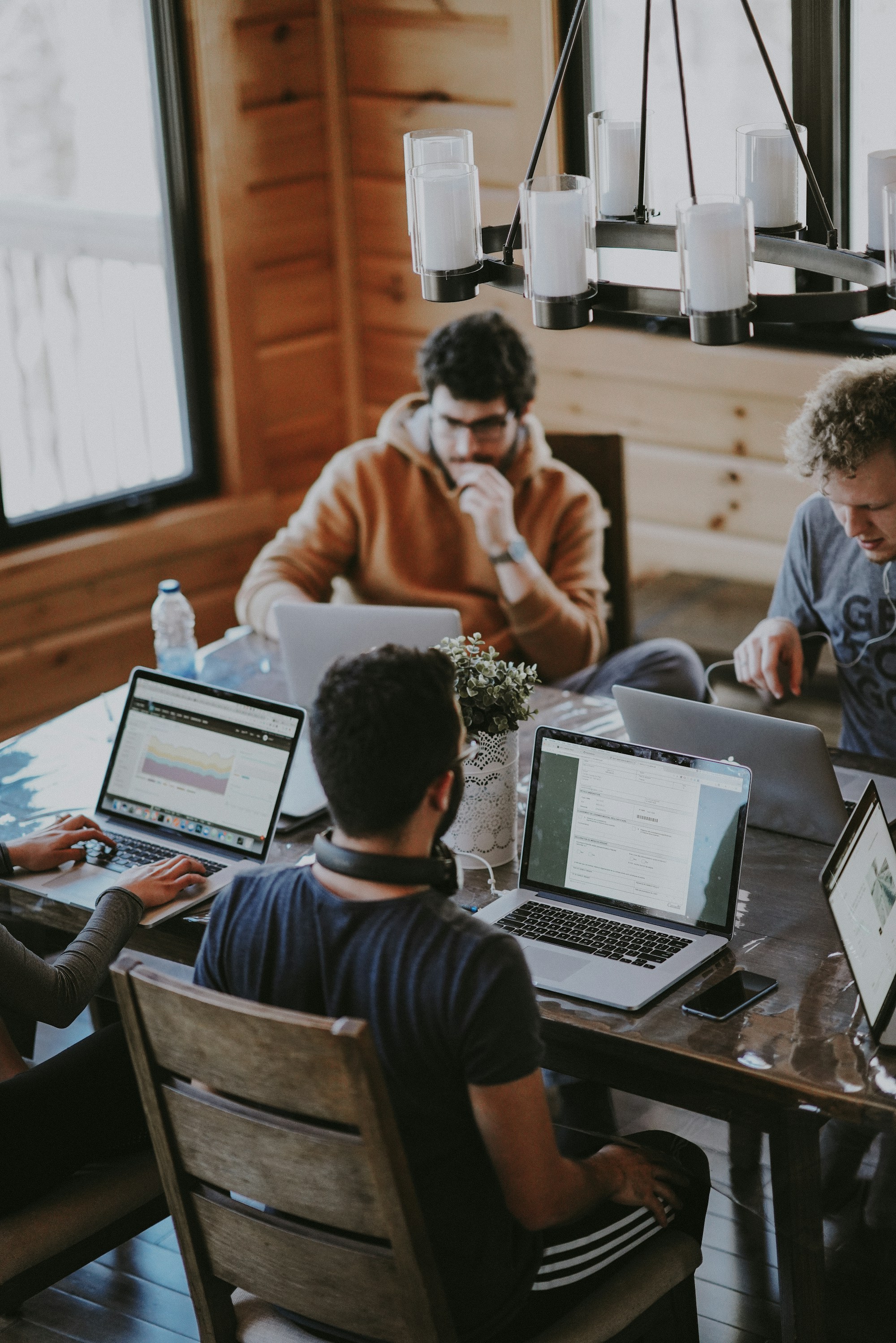 People collaborating around a table with laptops in a shared workspace